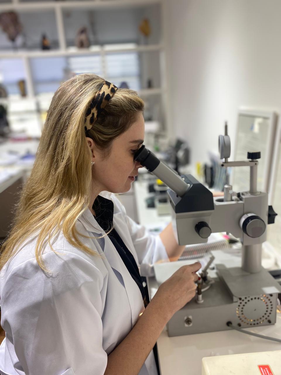Gemóloga CGA utilizando microscópio profissional - Análise técnica de gemas no laboratório